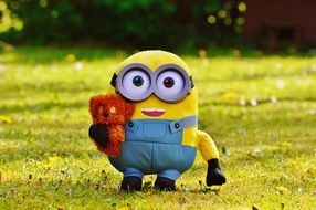 funny mignon with a toy in hands on green grass