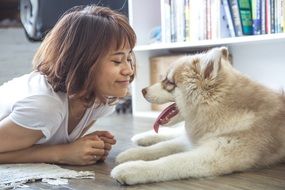 girl and a fluffy puppy are lying on the floor