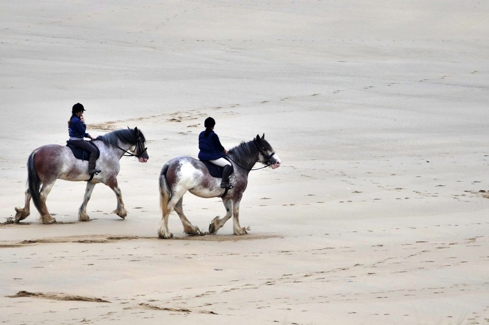 two horse riders on the beach