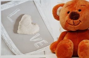 teddy bear sits next to the inscription love