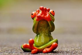 green frog sitting in the lotus position with hands raised