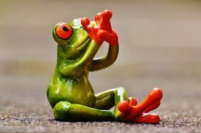 green toad sitting on the asphalt path