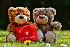 an envelope with an inscription love for mom in the hands of teddy bears
