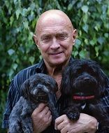 man with two black puppies