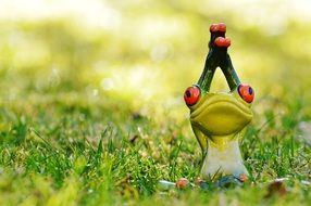 figure of a frog in a yoga pose on grass