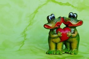 ceramic figurine of two frogs holding heart