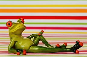green frog lays on a background of colored bands