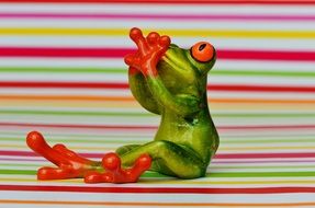 green frog sitting crossed legs on a background of colored bands