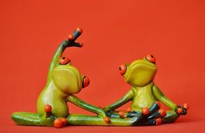 Two frogs doing yoga on a red background
