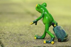 green walking frog figure with luggage