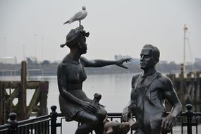 statue of a man and a woman on the shore