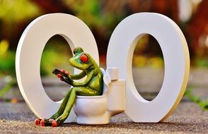 Funny toy Frog with mobile phone on Toilet