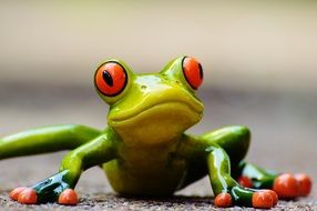 ceramic funny frog with orange eyes close-up on blurred background