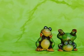 two ceramic frog on a green background