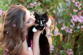 young woman kissing black cat