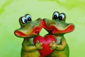 two frogs with a heart in his hands