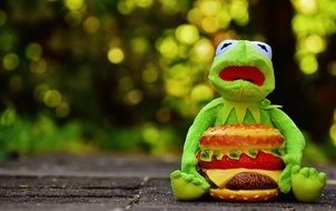 Kermit is sitting on the floor with cheeseburger