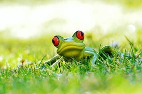 Closeup picture of green ceramic frog on the meadow