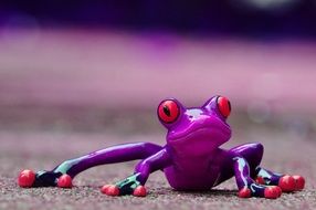 ceramic figure of a purple frog with orange eyes