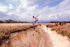 young man and Dog jumping through ditch