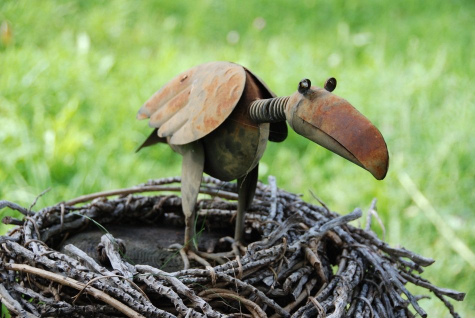 funny metal bird on nest outdoor