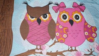 two pink owls are painted on fabric