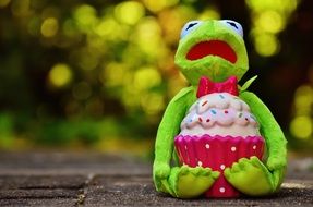 frog sitting on the pavement with a cupcake in hand