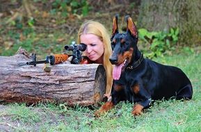 Doberman lies near the girl with a gun