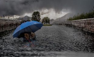 people under the blue umbrella on the road at rainy weather