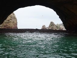 view of wildery coast through arch in rock, Peru, Ballestas Islands