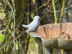 metal bird sits on a tower decoration in a garden