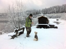 elderly man trains a dog outside the city in winter