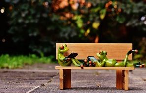 Frogs with tablets in hand on a bench