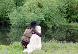 mistress with a big white dog on the bank of the pond