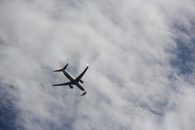the plane is flying under the white clouds