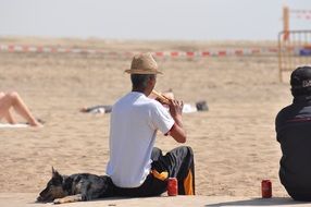 Man rests on the beach with his dog