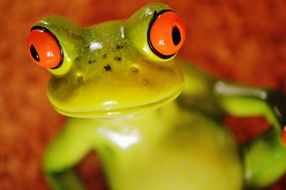 ceramic green frog with big red eyes on the floor