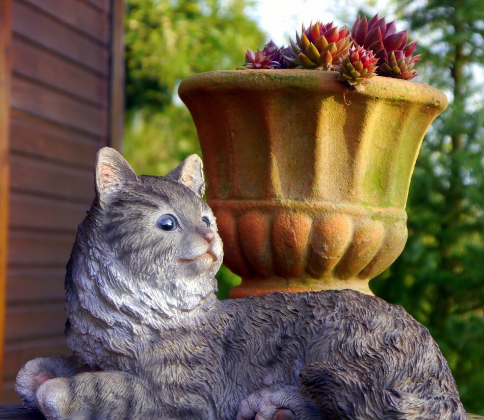 sculpture of a cat near a potted flower in the garden