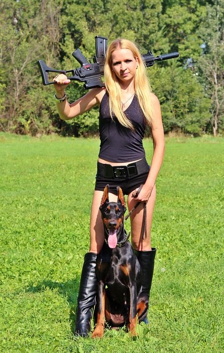 woman with rifle and doberman