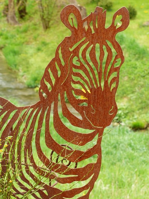 zebra metal figure on a background of trees