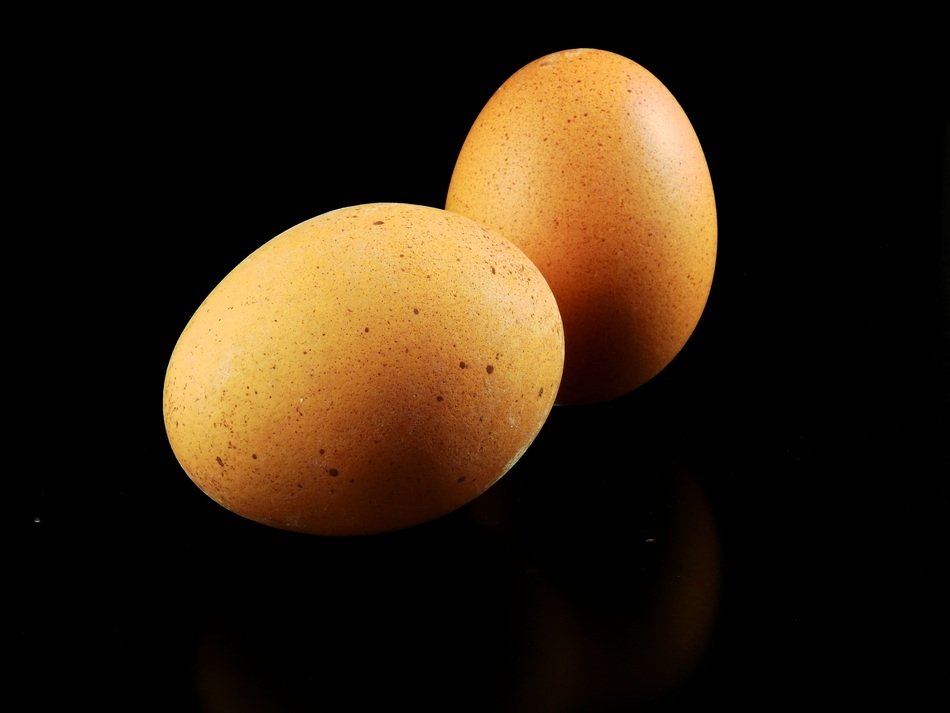 two hen's eggs in the black background