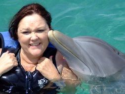 dolphin kissing a woman in water