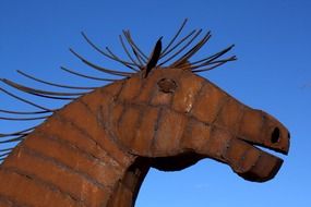 metal sculpture of a horse against the blue sky