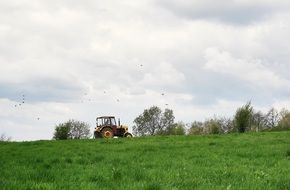 distant view of a tractor on a green meadow