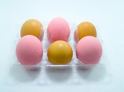 yellow and pink eggs in an egg carton