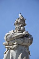 Seagull at top of male Statue at sky