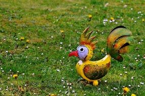 decorative element in the garden in the form of a yellow rooster