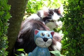 fluffy domestic cat with a cat garden figure