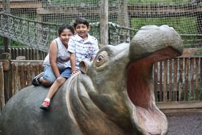 children on a stone sculpture of a hippopotamus