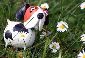 figurine of a dog in the grass with daisies